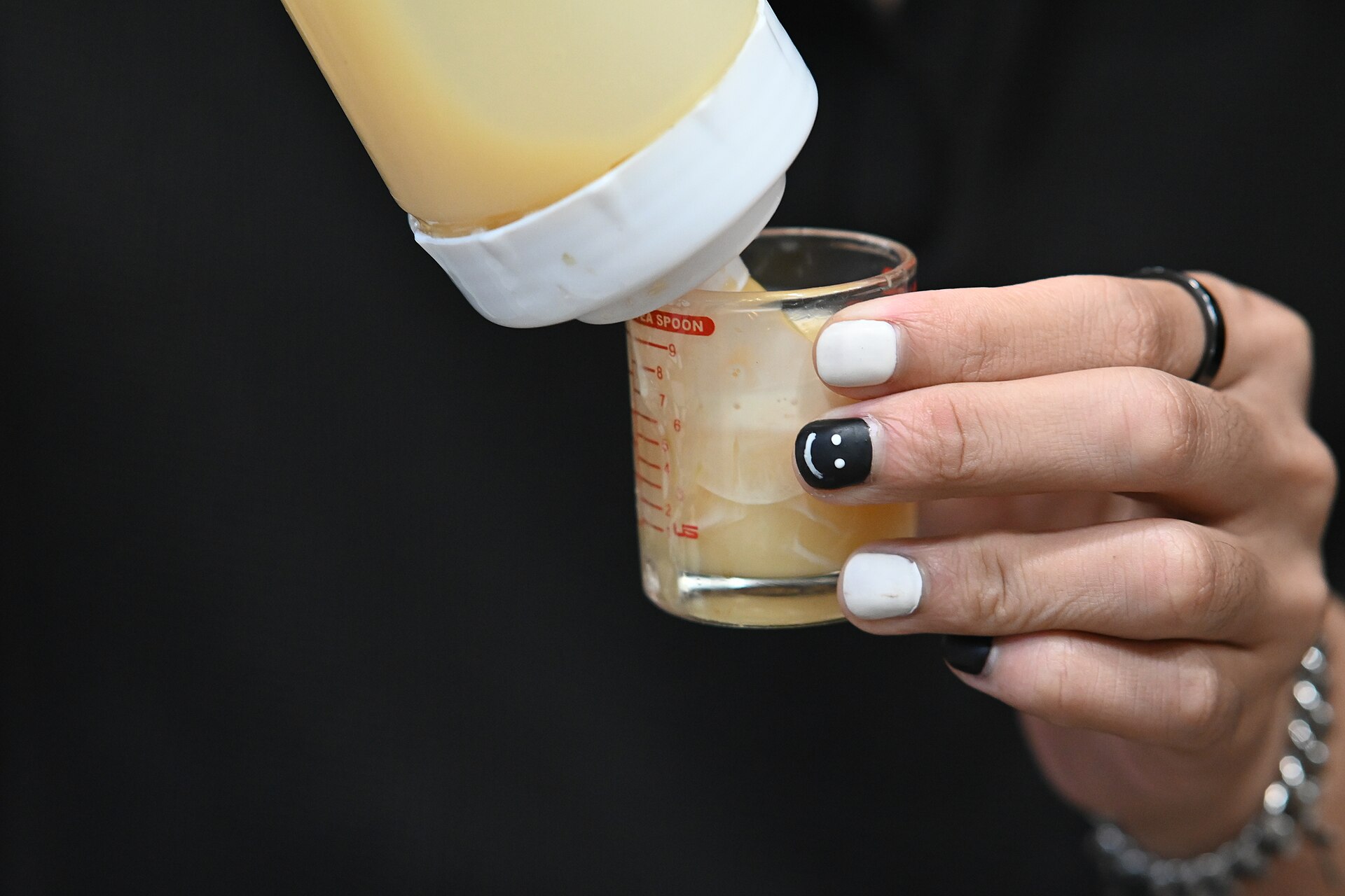 Manos con diseño de uñas en blanco y negro junto a frascos de esmalte sobre una mesa de trabajo.